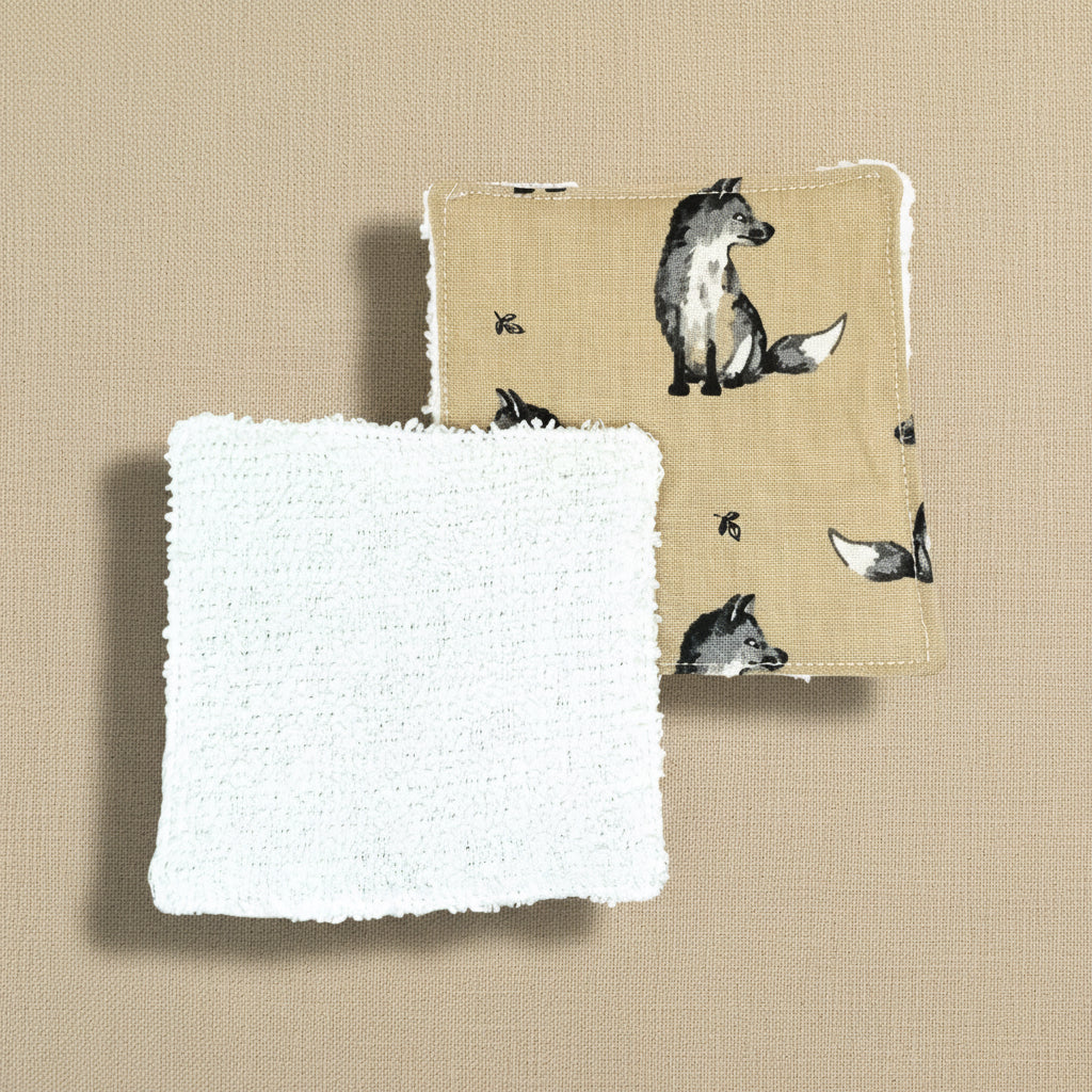 Two fox themed square reusable face wipes, one shows fox fabric side, one shows white flannel side