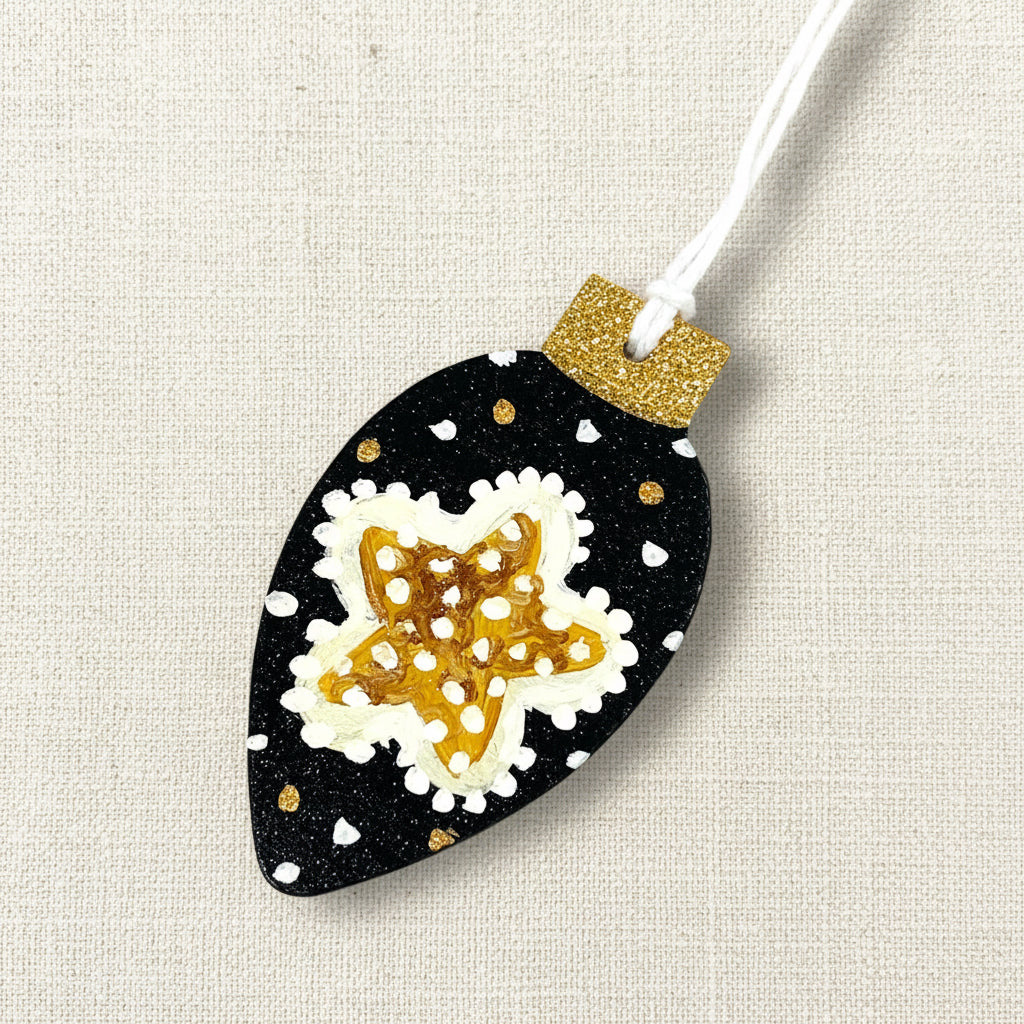 Decorative wooden Christmas tree ornament with a starfish design on a black background, hanging from a string.