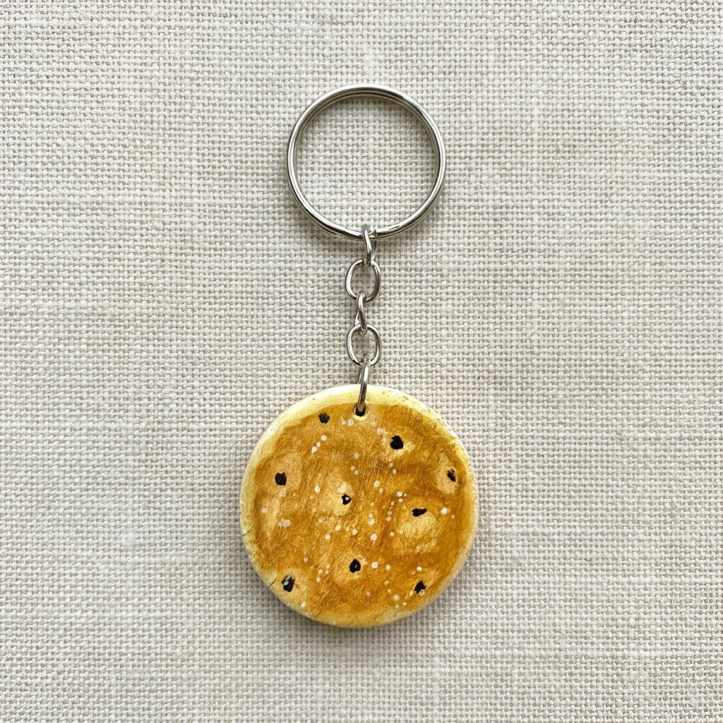 Round wooden keychain painted to look like a Welsh cake on neutral background 