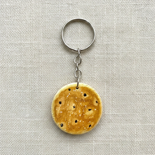 Round wooden keychain painted to look like a Welsh cake on neutral background 