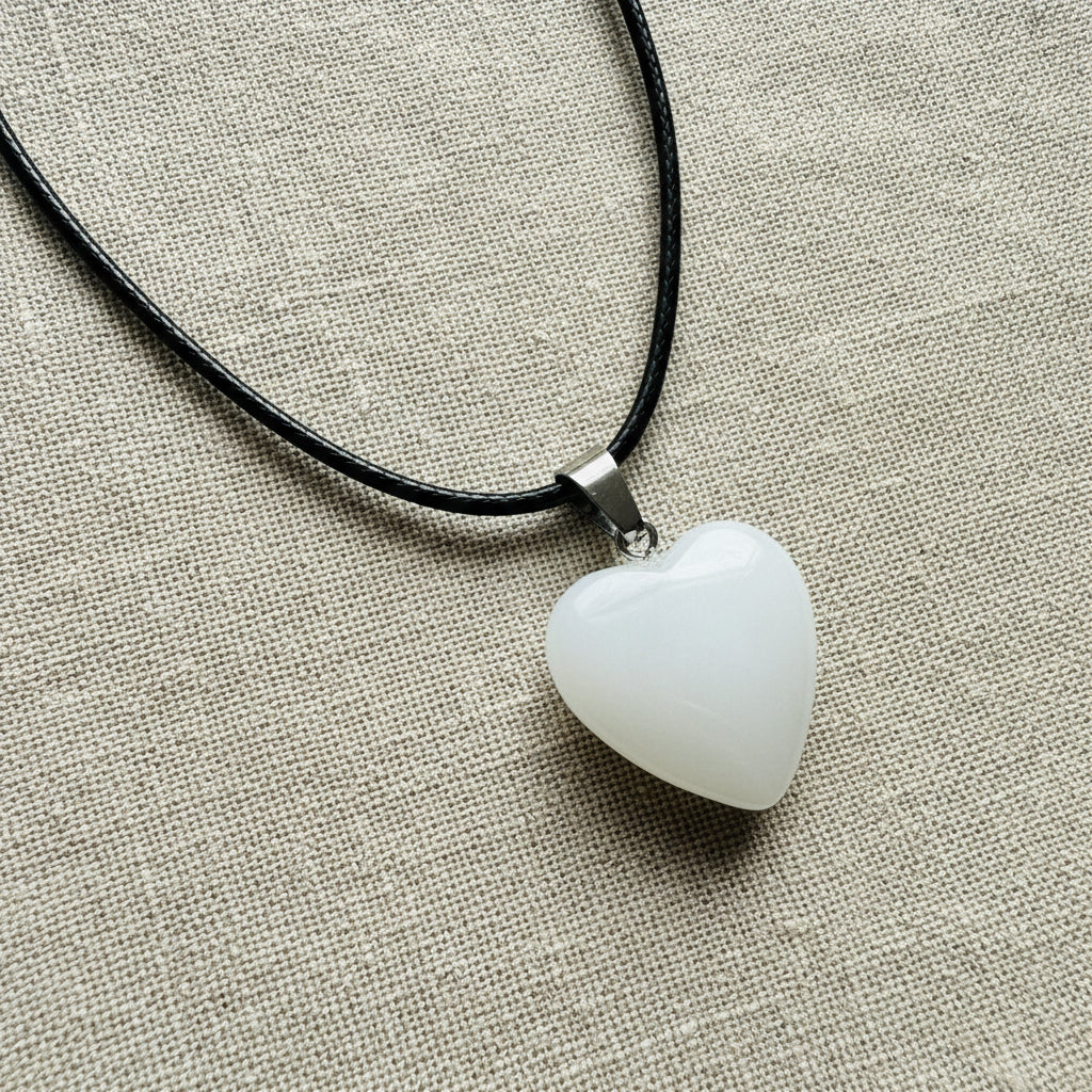 White Heart-shaped pendant on a black cord against a light background