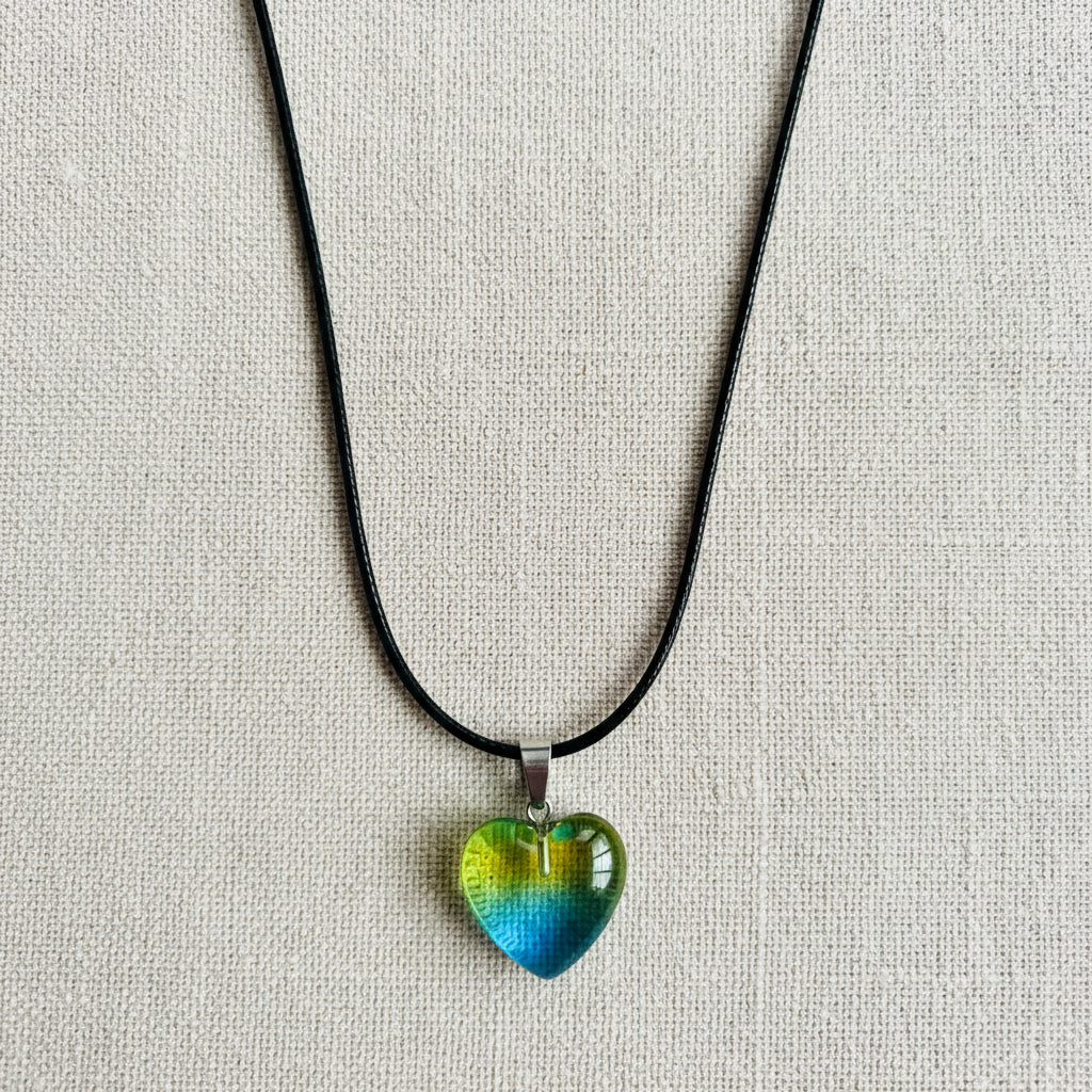 Heart-shaped pendant on a black cord against a neutral background