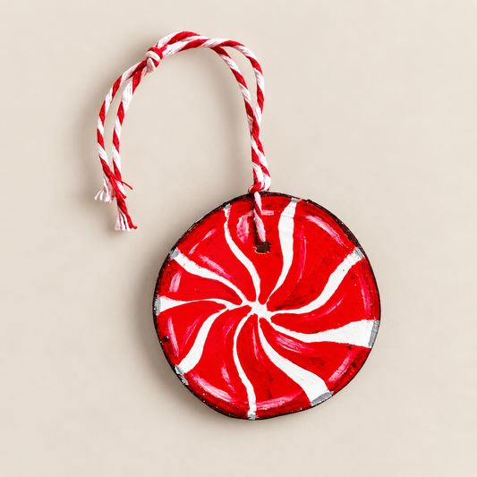 Hand-painted natural wood slice Christmas ornament with a red and white peppermint swirl design and twisted hanging cord