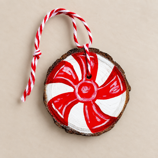 Natural wood slice hand painted with a red and white peppermint candy cane-style design and finished with twisted hanging twine.