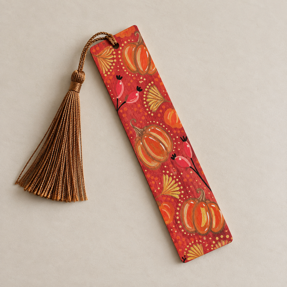 Hand-painted wooden autumn bookmark decorated with colourful pumpkins and botanical details, finished with a brown tassel.