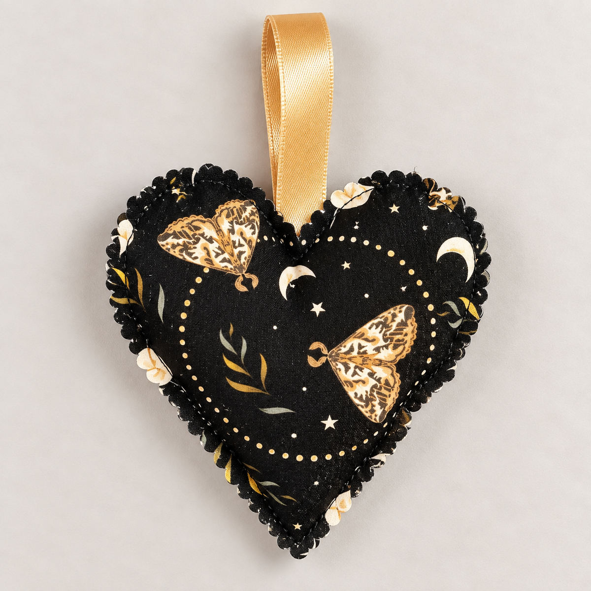 Handmade black fabric heart hanging decoration featuring gold moths, crescent moons, stars and botanical details, with a gold ribbon loop