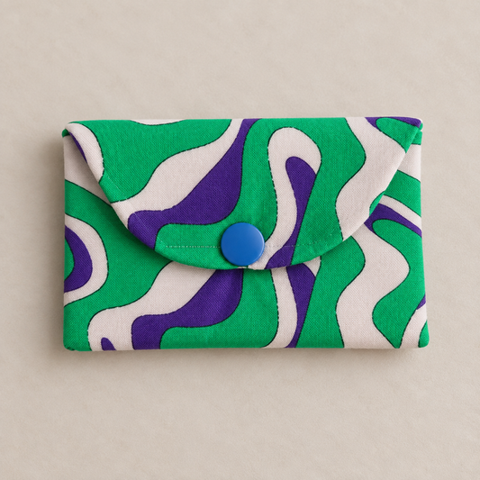 Small handmade fabric card wallet in green, purple and cream abstract print with a blue snap fastening.