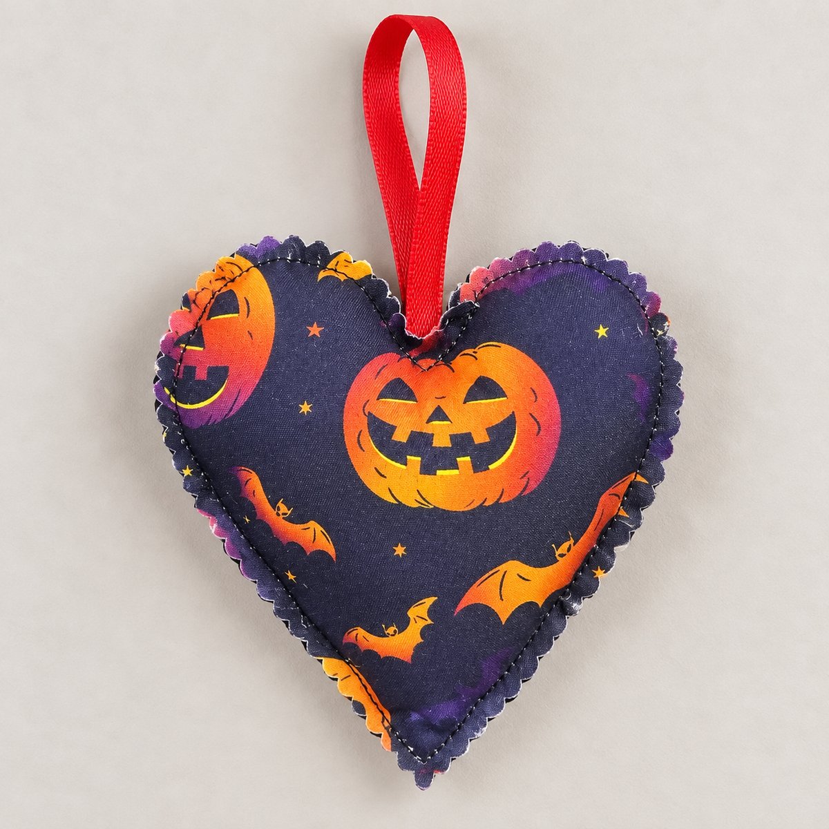 Handmade Halloween fabric heart decoration featuring orange jack-o’-lantern pumpkins, bats and stars on dark navy fabric, with a red hanging loop