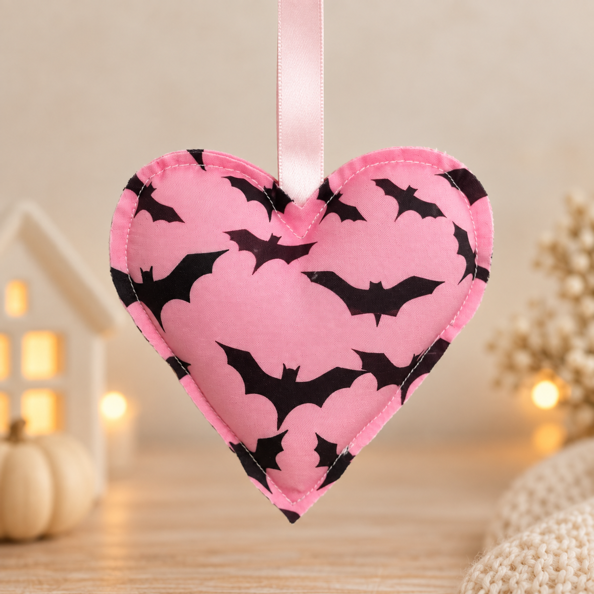 Handmade pink fabric Halloween heart ornament decorated with black bats and finished with a pale pink satin hanging ribbon.