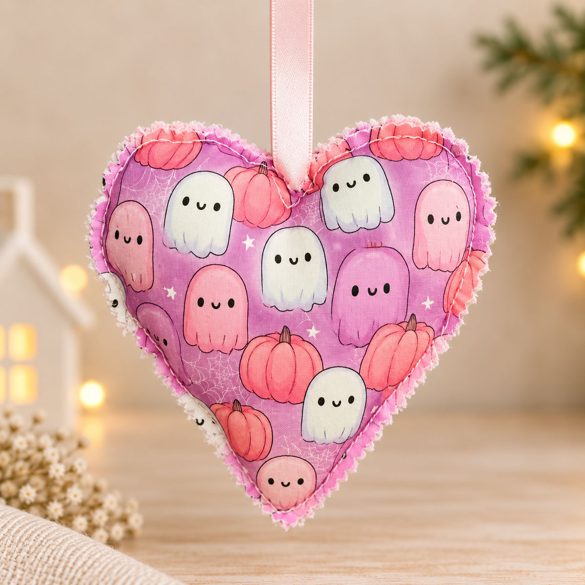 Handmade pink and lavender Halloween fabric heart ornament featuring cute ghosts and pumpkins with a baby pink hanging ribbon.