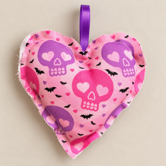 Handmade pink fabric Halloween heart with purple and pink skulls, black bats and small hearts, with a purple ribbon loop for hanging.