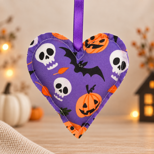 Handmade purple fabric Halloween heart ornament decorated with bats, skulls and pumpkins, finished with a purple satin hanging ribbon.