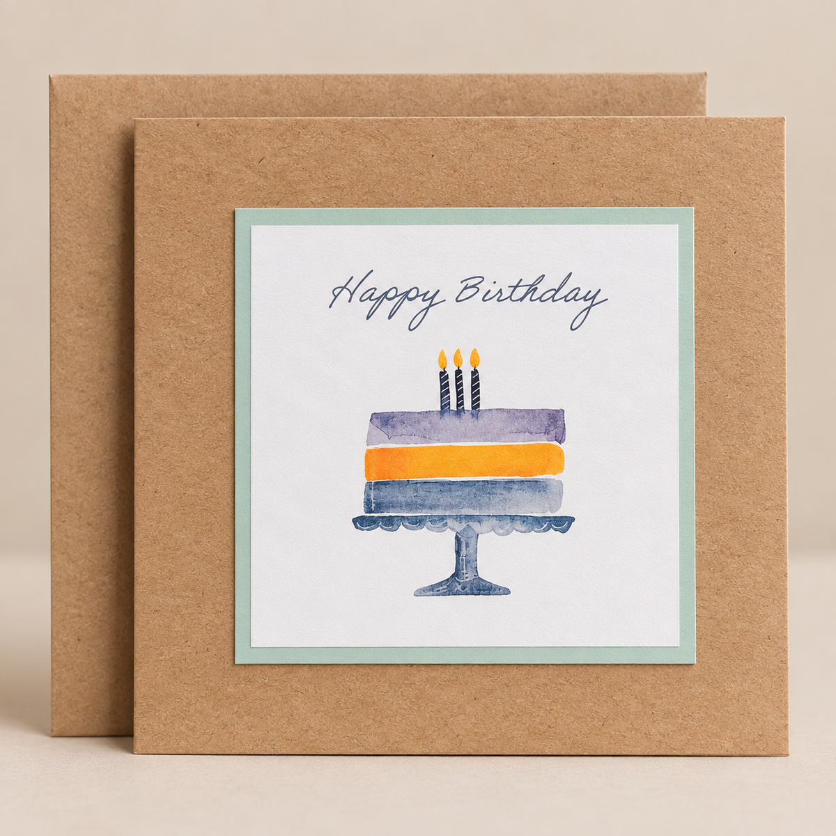 15 x 15 cm natural Kraft birthday card featuring a watercolour birthday cake with three candles and Happy Birthday lettering, with a Kraft envelope