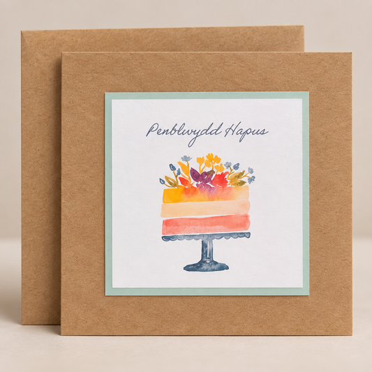 15 x 15 cm natural Kraft Welsh birthday card featuring a colourful watercolour floral cake and Penblwydd Hapus lettering, with a Kraft envelope